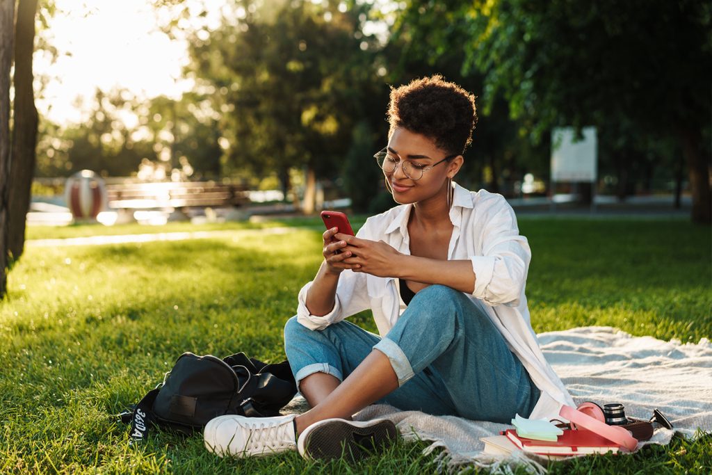Mulher olhando para o telefone ao sol no parque