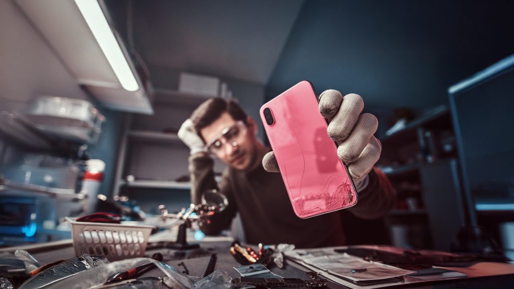 man holding phone with broken back glass