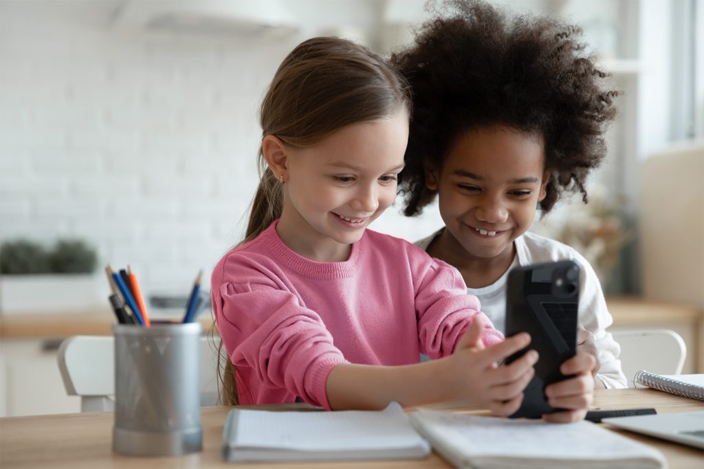 two young girls playing games on their smartphone at the table