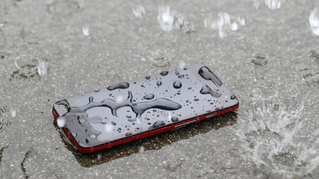 phone sitting on ground covered in water from the rain