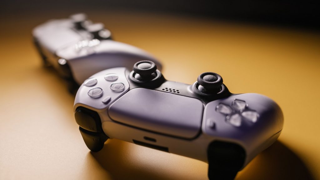 two ps5 controllers sitting on a desk